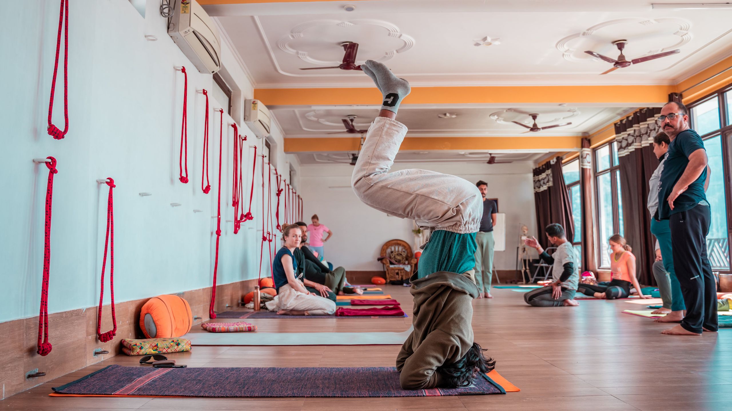Yoga class in studio with large mandala on the wall