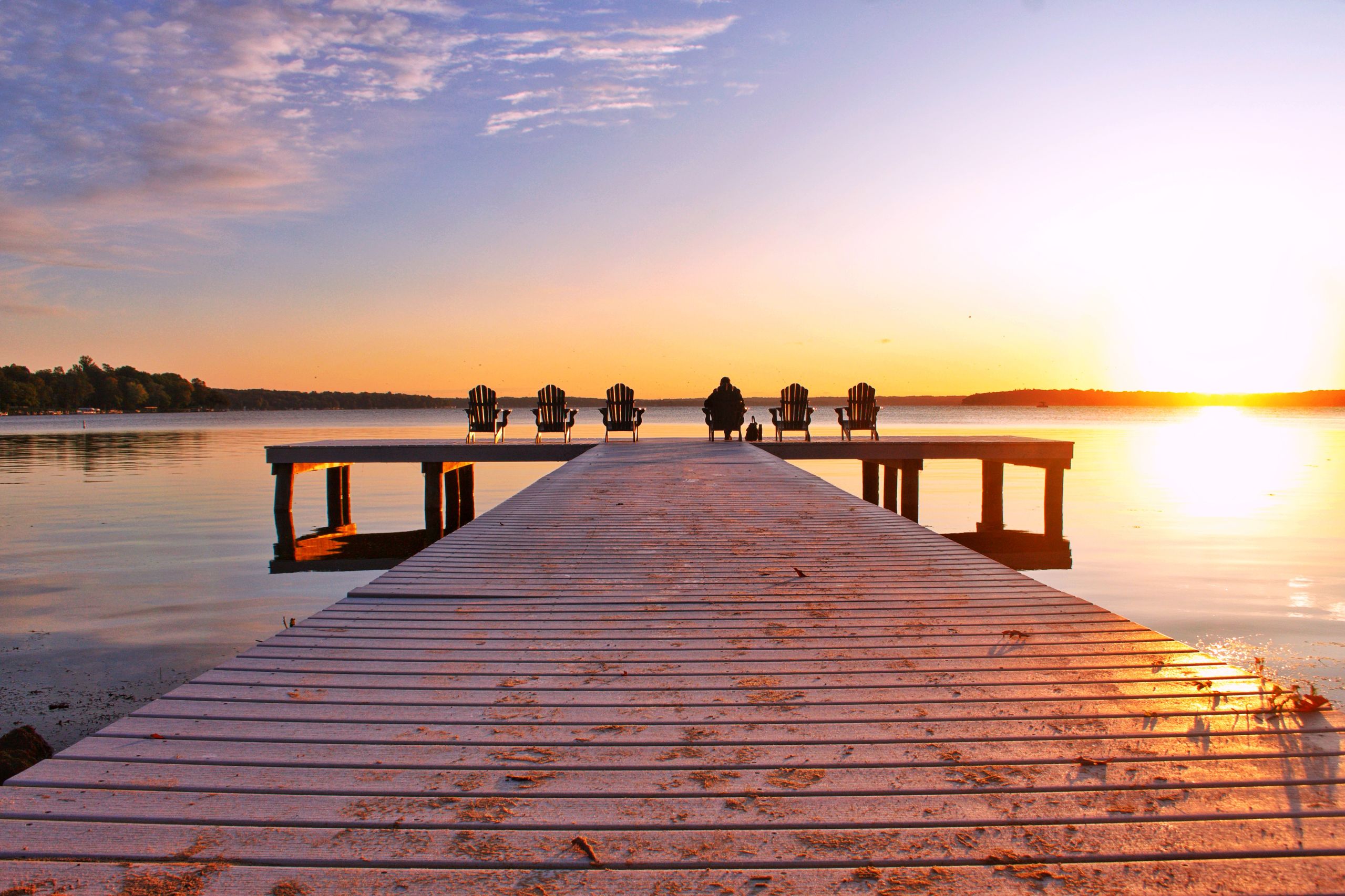 Group meditation on wooden deck facing mountain lake at golden hour