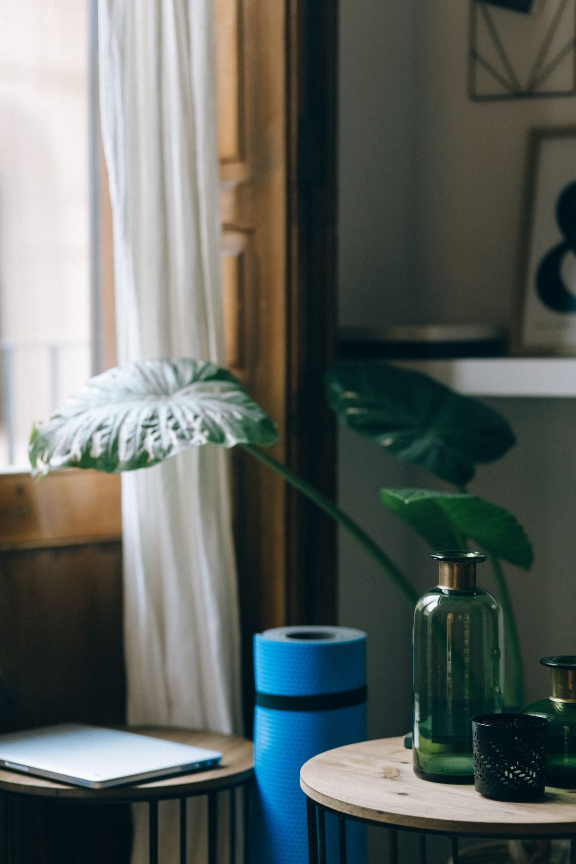Sunlit yoga studio corner with green mat, towel, blocks, and Monstera plant