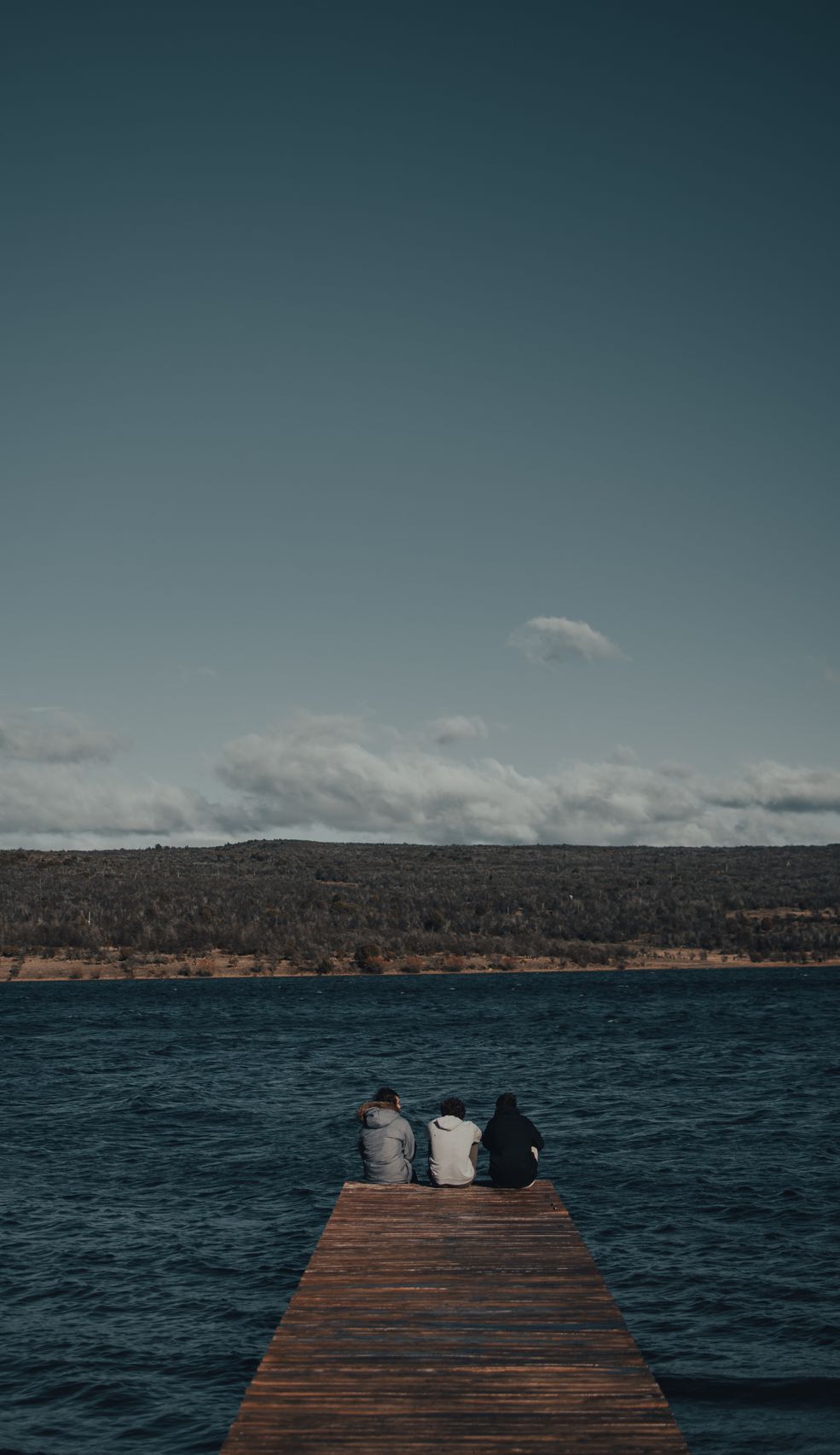 People meditating on a dock facing a lake